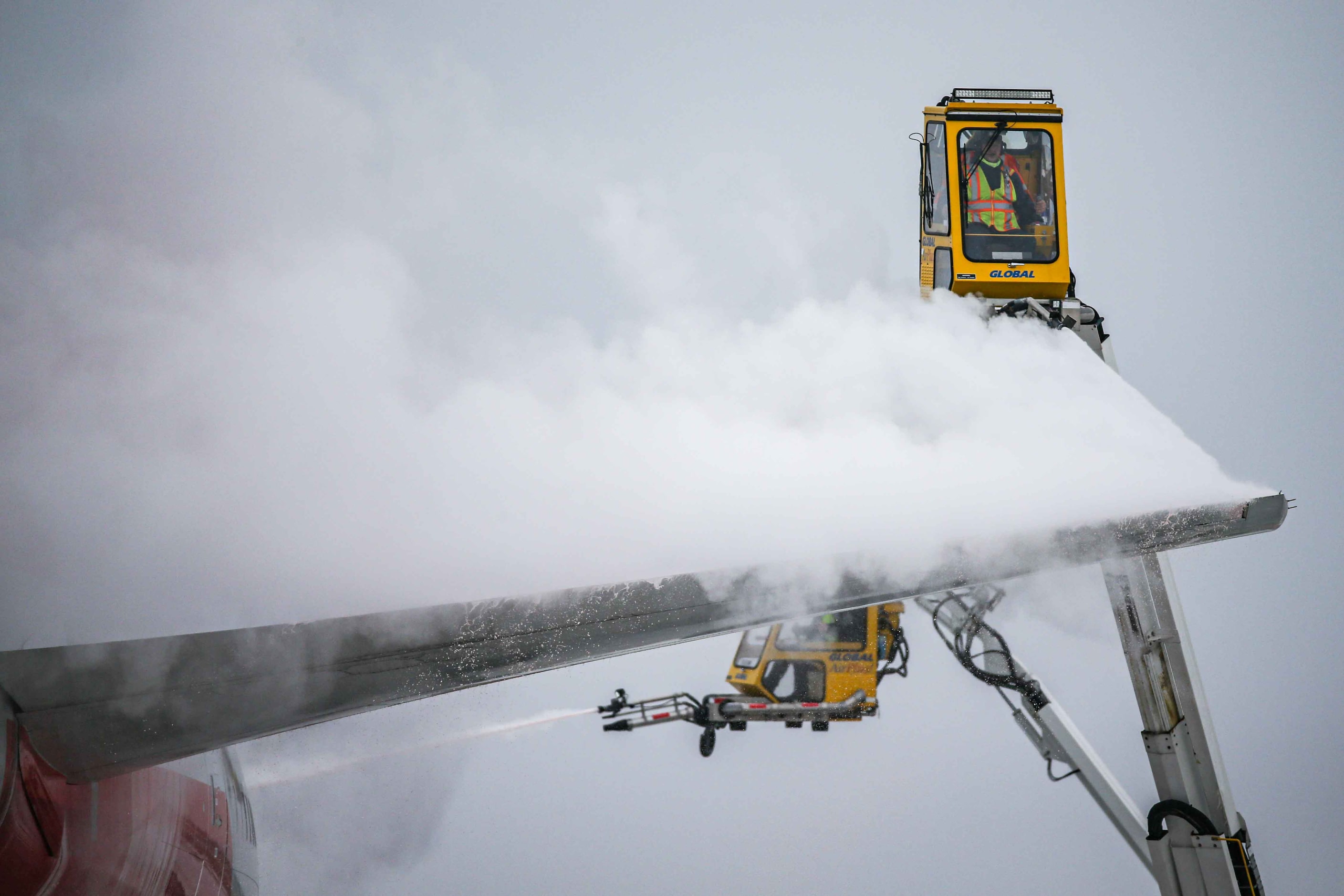 An American Airlines jet is de-iced at DFW International Airport before takeoff as winter...