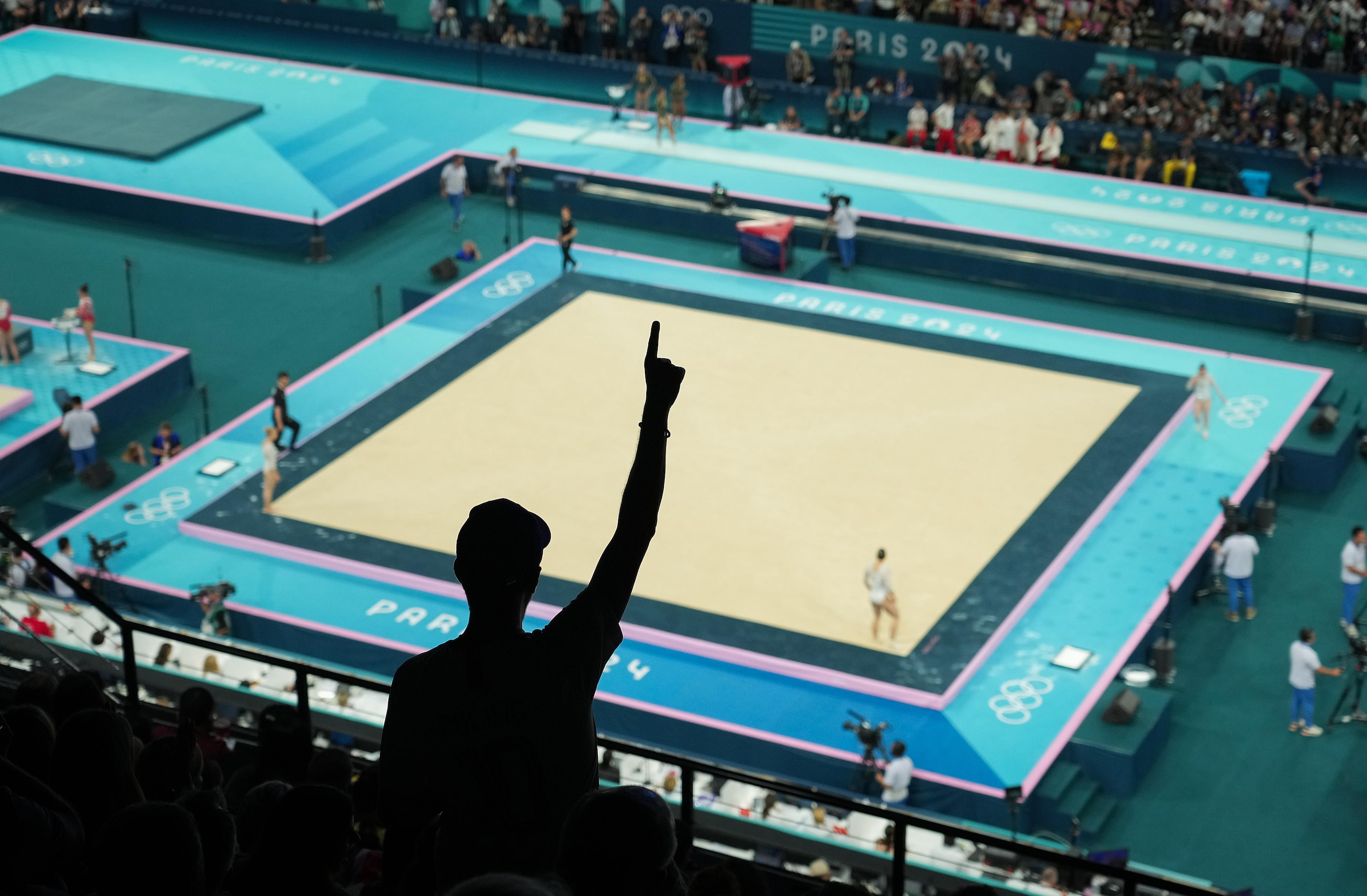 Fans cheer as the United States rotates to compete on the floor during the women’s...