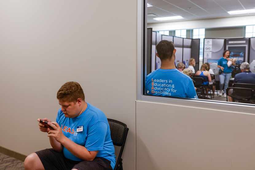 Event leader Michael Susens, who has Asperger’s syndrome, plays a game on his phone as he...