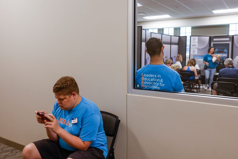 Event leader Michael Susens, who has Asperger’s syndrome, plays a game on his phone as he...