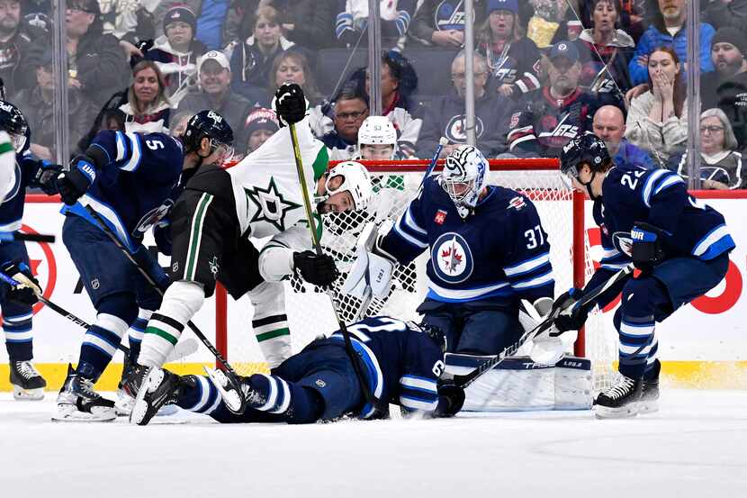 Dallas Stars' Jamie Benn, left, tries to get the puck under Winnipeg Jets' Nino Niederreiter...