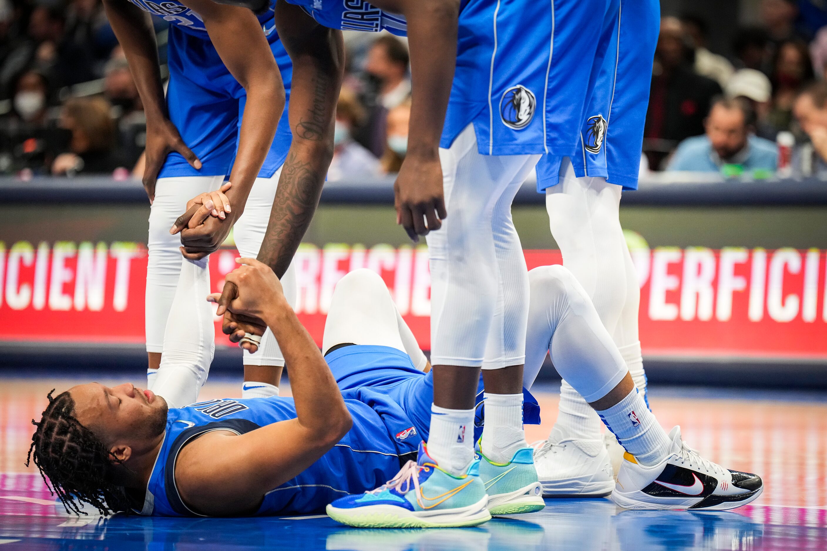 Dallas Mavericks guard Jalen Brunson is helped off the floor by teammates after drawing a...