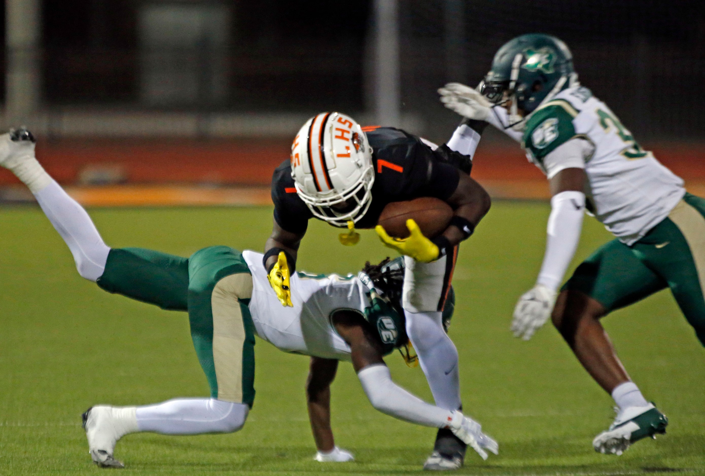 Lancaster High Da’Kariean Johnson (7) goes flying, as he is stopped by two DeSoto High...