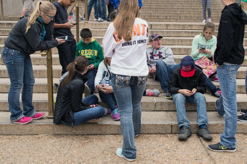  A group of teens check their smartphones during a Washington D.C. field trip.