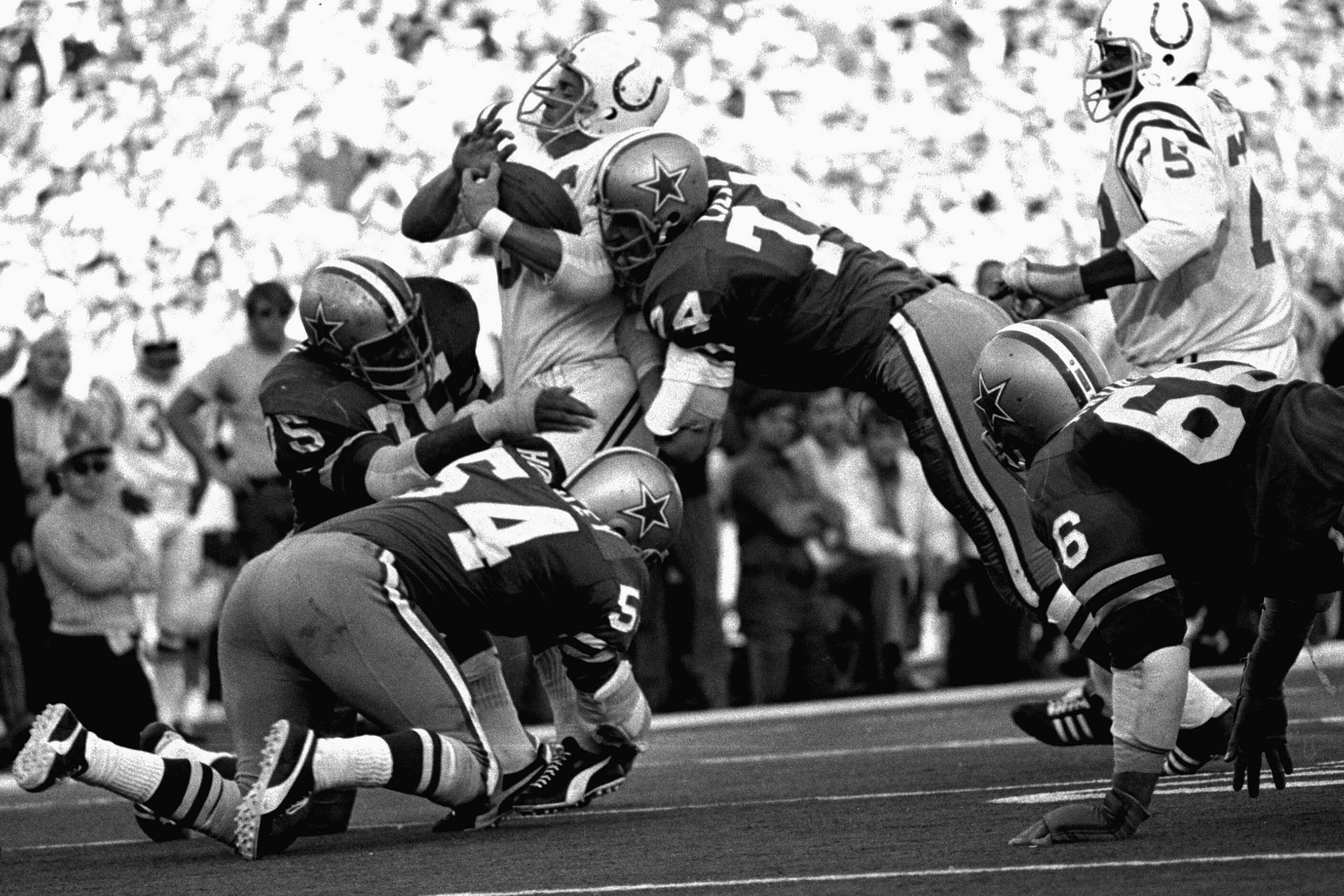 A trio of Dallas Cowboys gang tackle Baltimore Colts linebacker Mike Curtis following his...