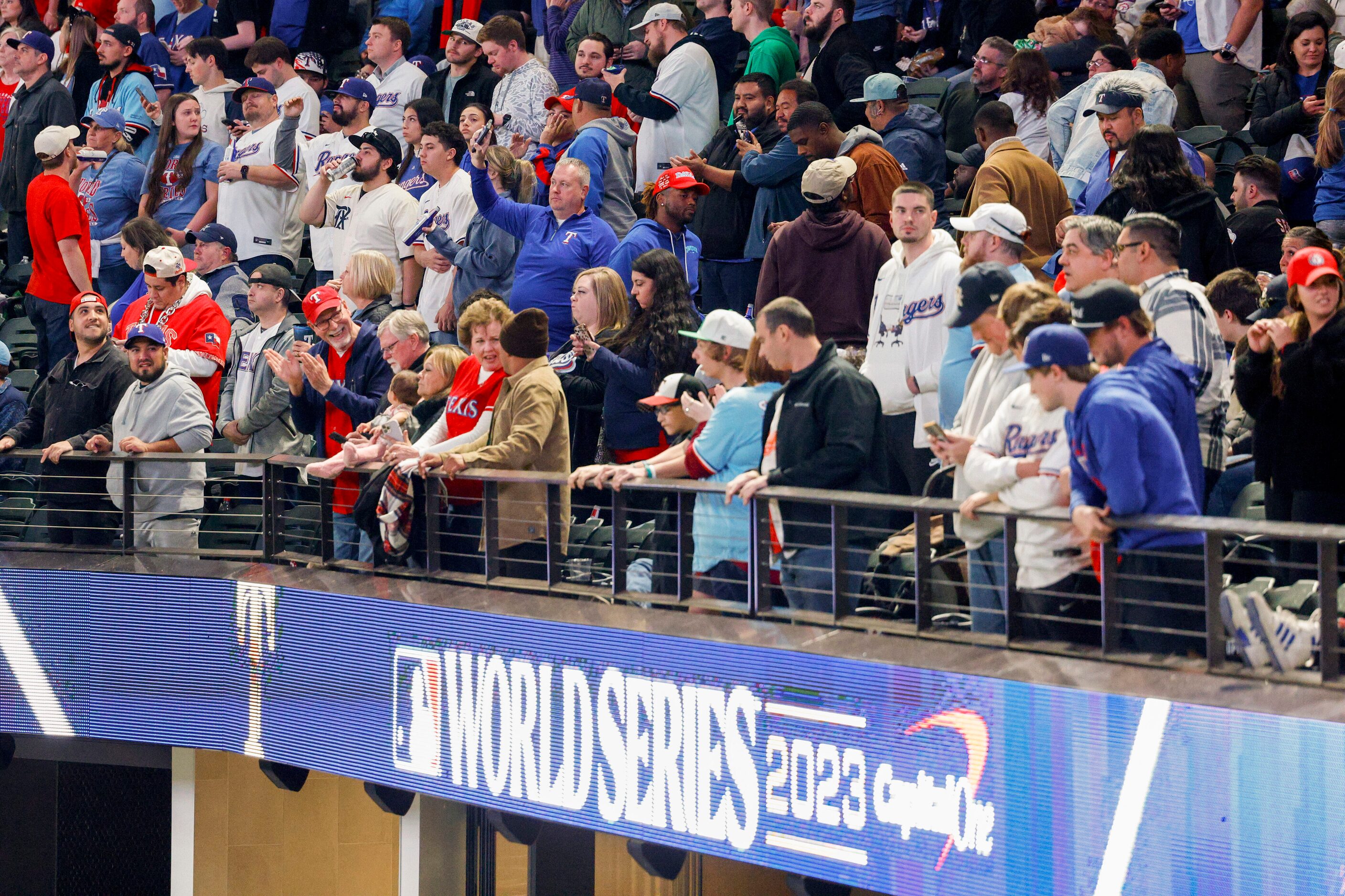 Fans stand during the seventh inning stretch in Game 3 of the World Series between the Texas...