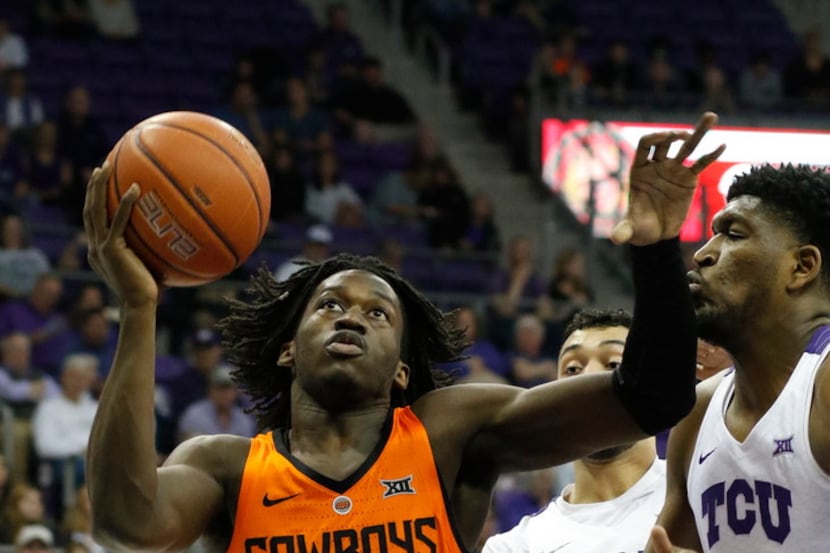 Oklahoma State guard Isaac Likekele (13) drives to the basket, defended by TCU guard Alex...