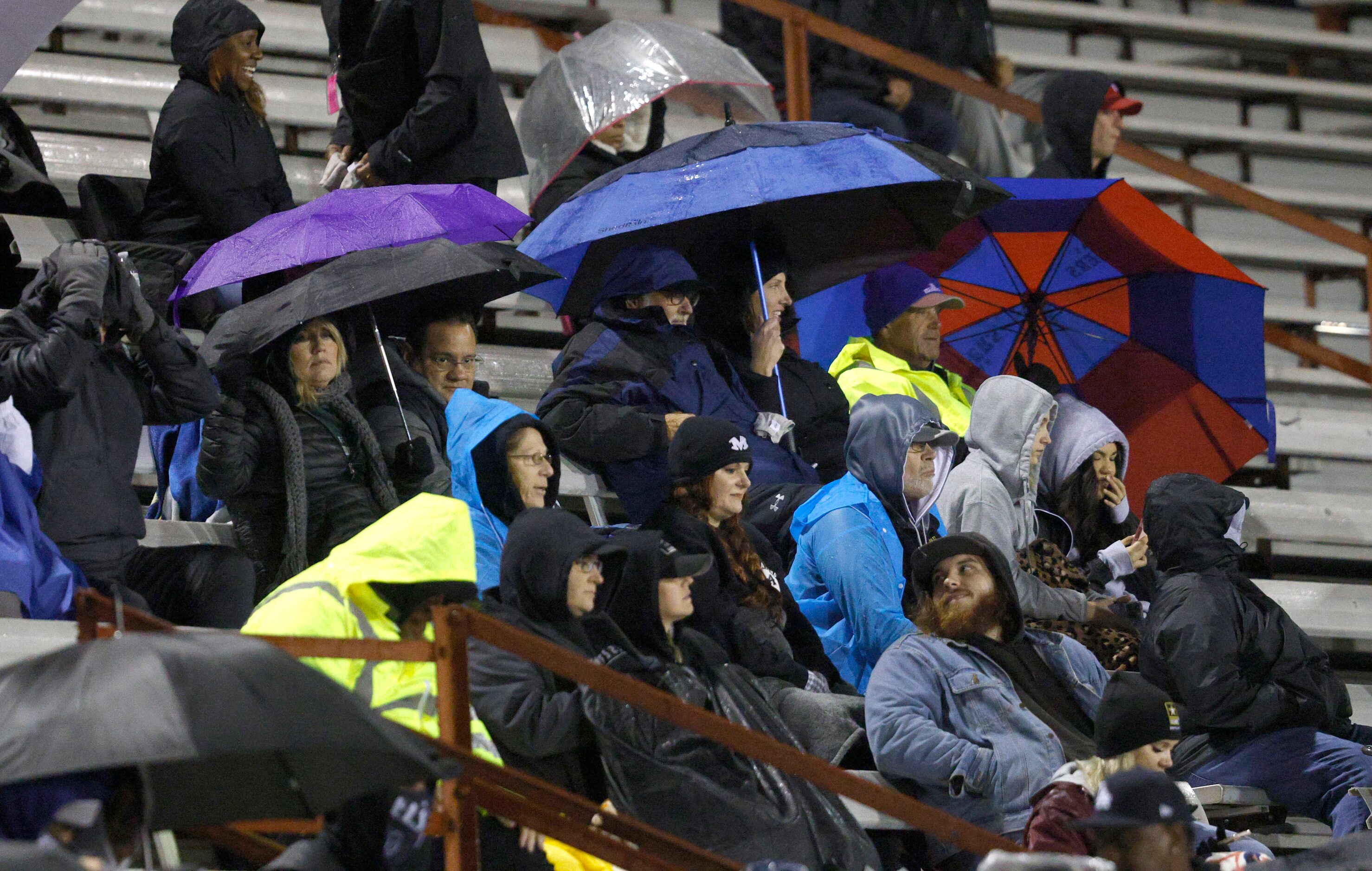 People sit on the stand in the rain during the first half of a high school Class 6A Division...