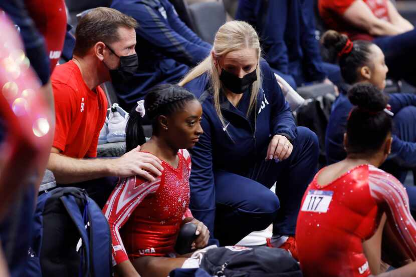 Coaches Laurent Landi (left) and Cecile Landi talk with Simone Biles after she competed on...