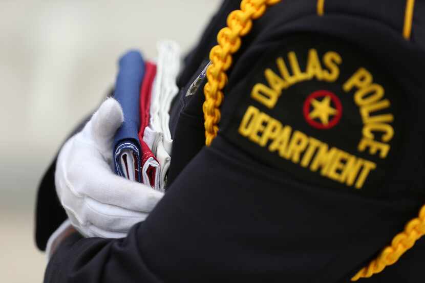 A Dallas Police Department Color Guard holds onto a flag before the guard raises the Texas...