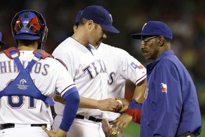 Texas Rangers' Colby Lewis hands the ball over to manager Ron Washington as catcher Robinson...