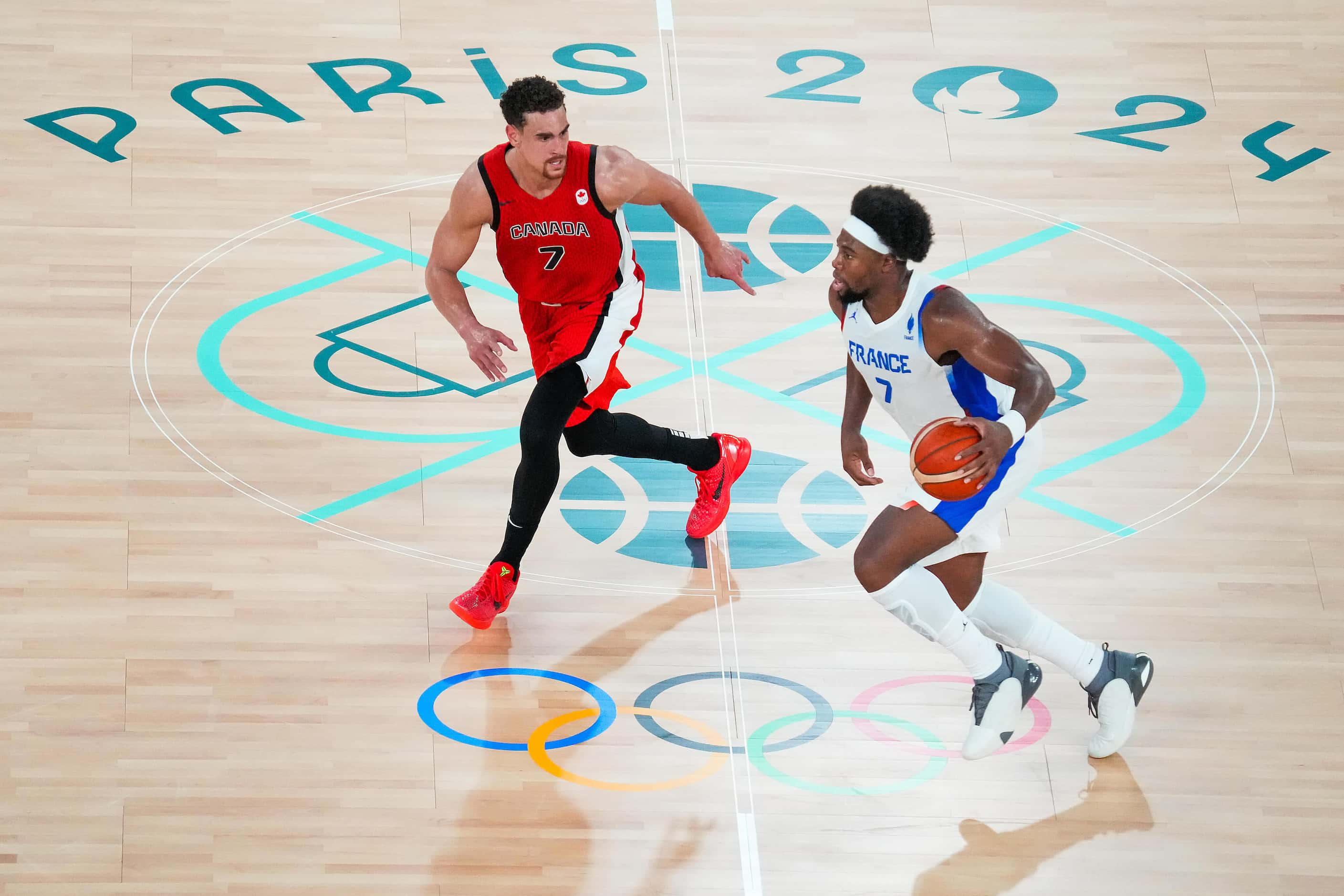 Guerschon Yabusele of France brings the ball up the floor as Dwight Powell of Canada defends...