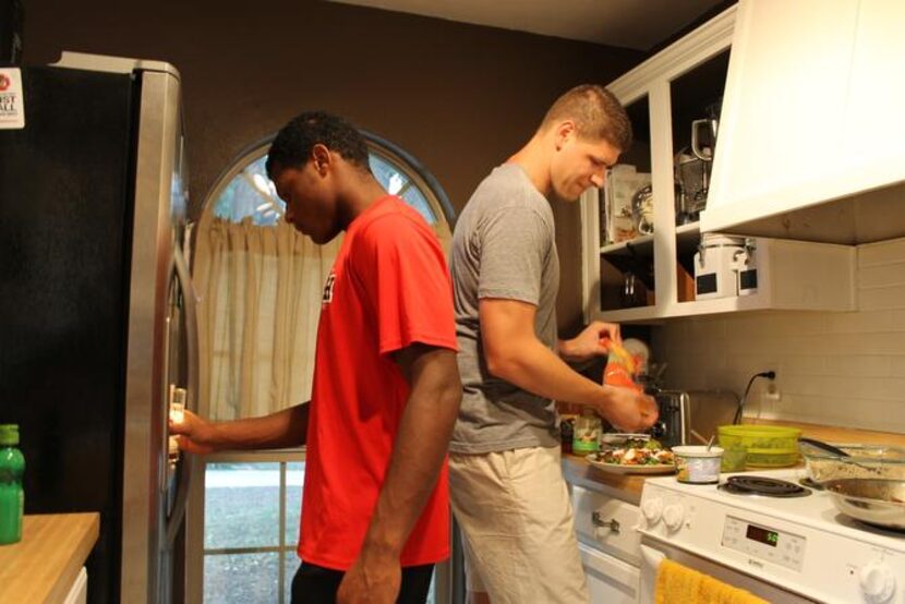 
LaQuantis Davis (left) fills his cup with water as Zach Garza puts food on his plate for...