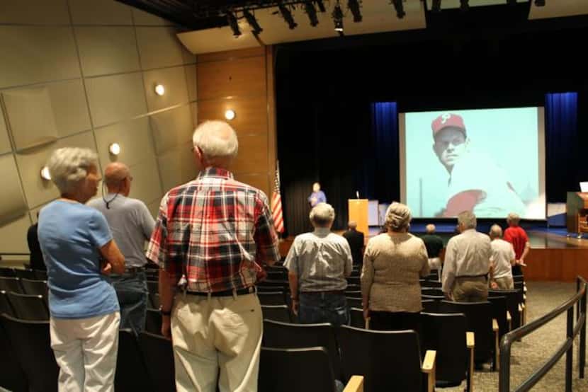 
Attendees rise for the national anthem before an author’s talk by Paul Rogers, who wrote a...