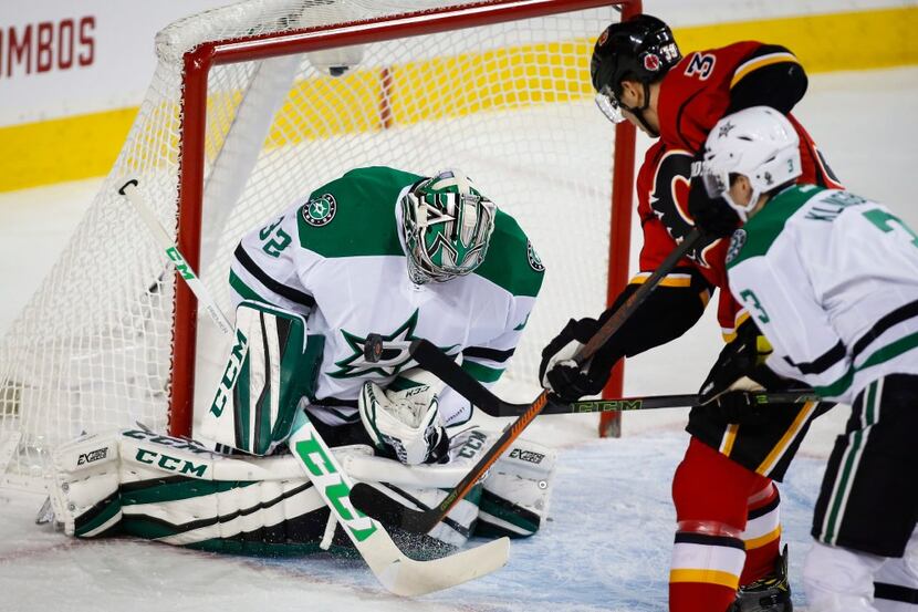 Dallas Stars goalie Kari Lehtonen, left, from Finland, blocks a shot from Calgary Flames'...