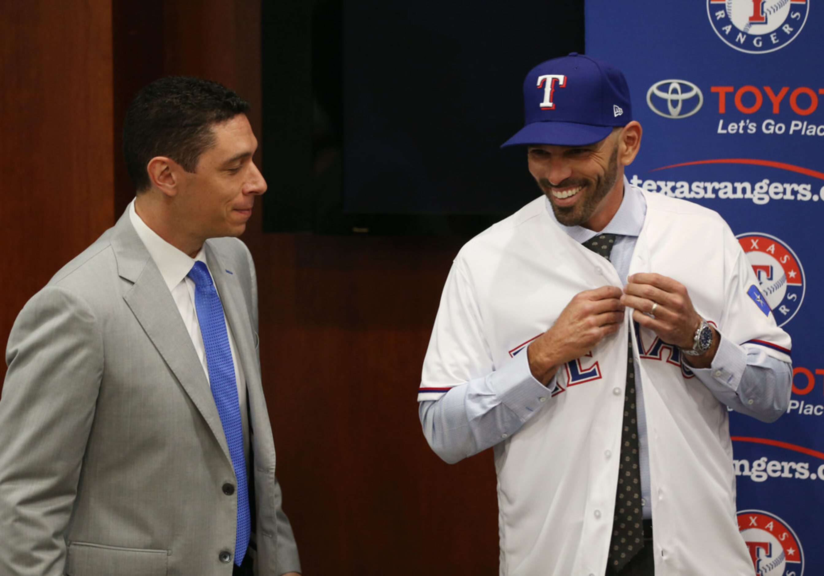 Texas Rangers' new manager Chris Woodward puts on his jersey next to General Manager Jon...