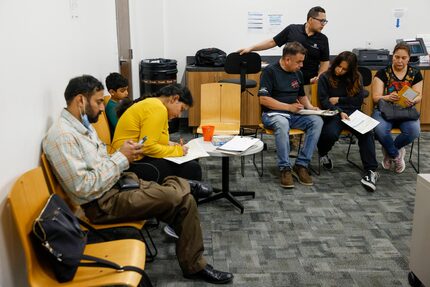 Passport office manager Edgar Miranda (top right) helps passport applicants with their...