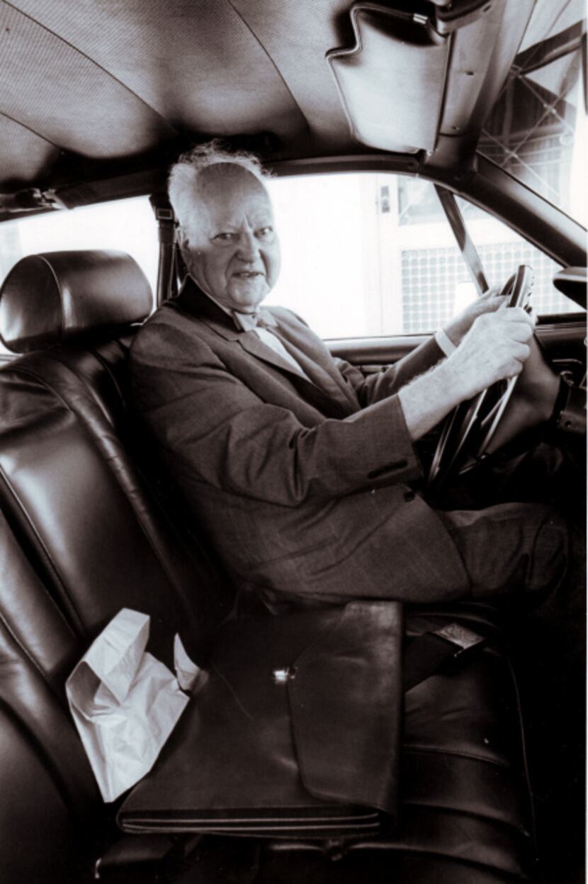 Texas oil billionaire H.L. Hunt, sits in his old car with his sack lunch he took to work...