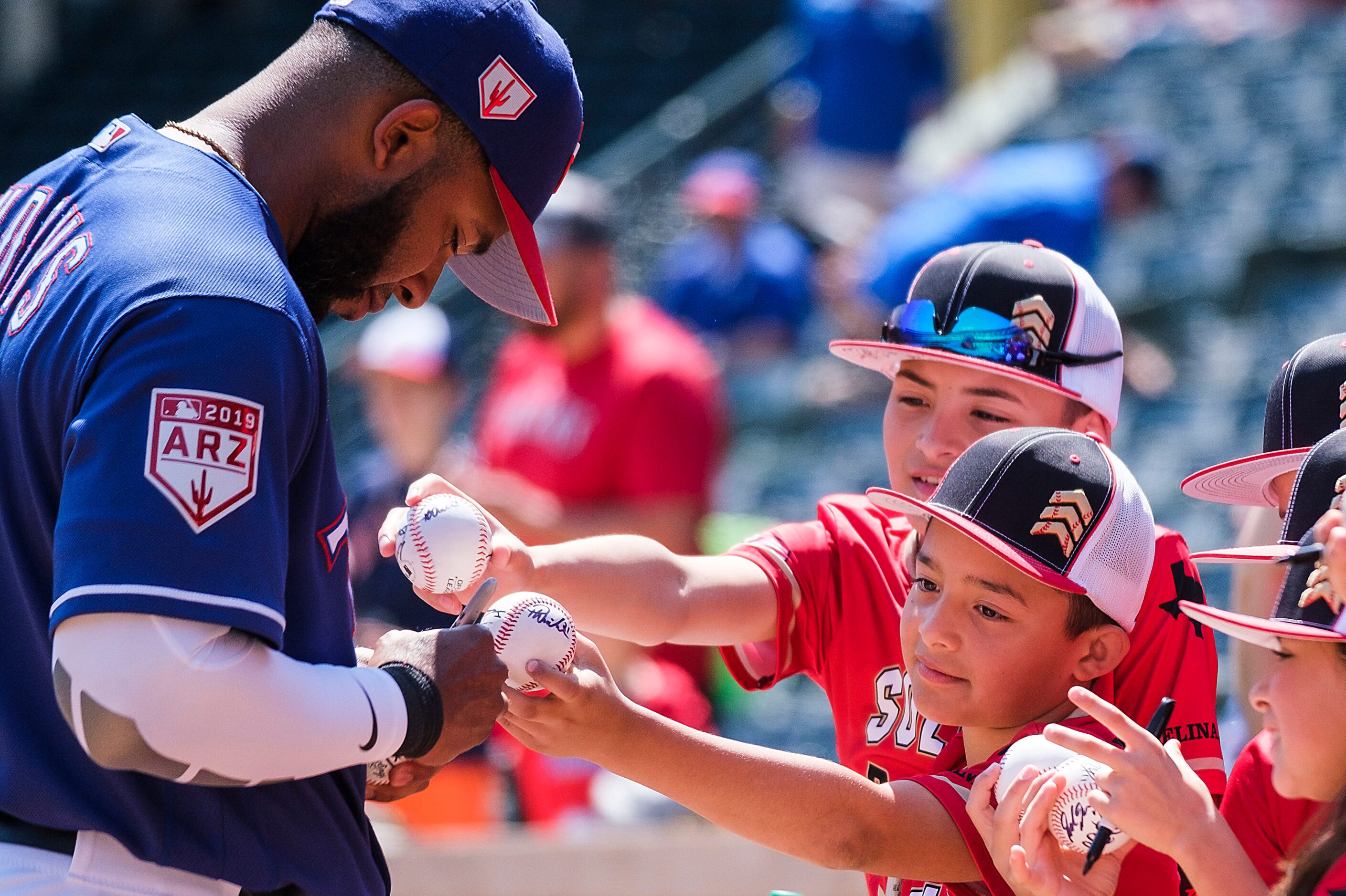 Texas Rangers shortstop Elvis Andrus signs autographs before a spring training baseball game...