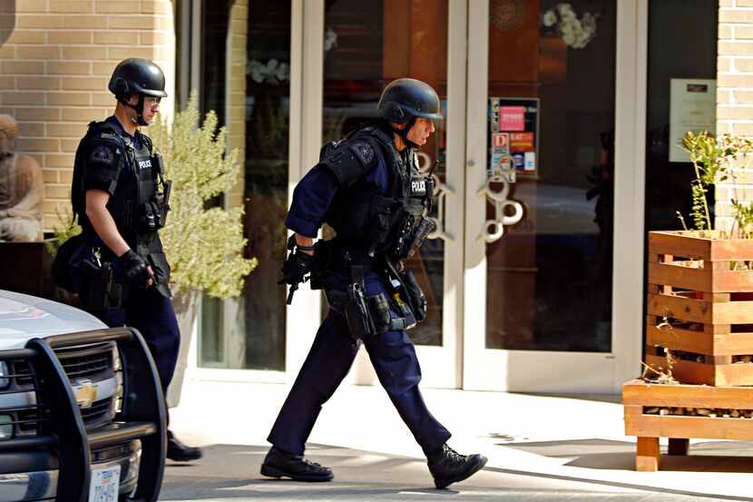 Police officers walk around a corner during a standoff with an armed person, Tuesday, March...