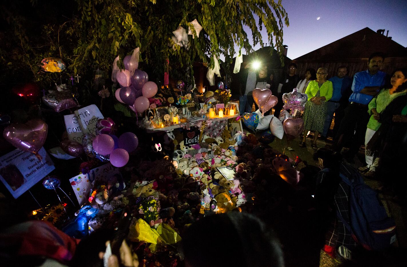 People gather at a memorial for missing 3-year-old Sherin Mathews on Sunday at a tree behind...