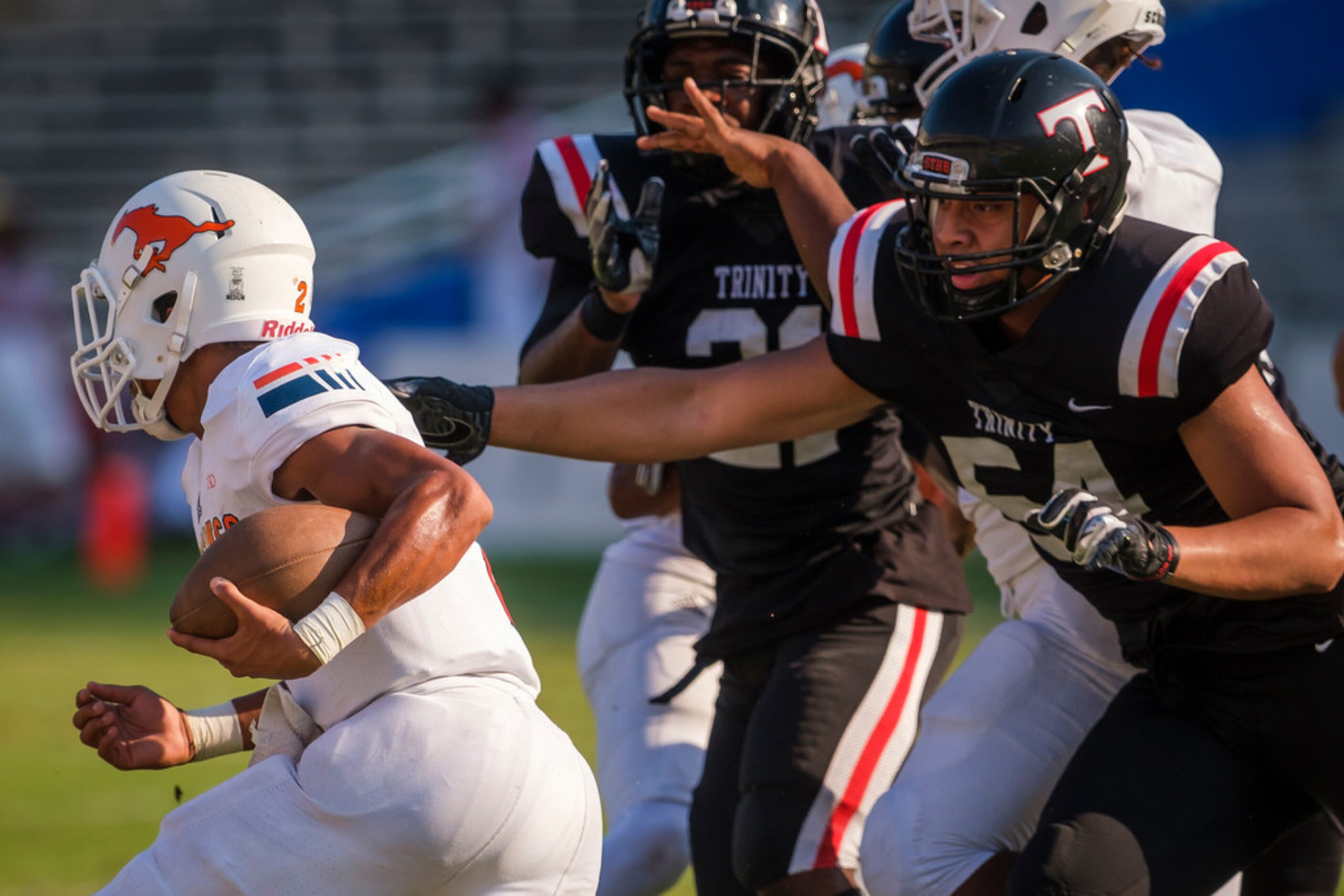 Sachse quarterback Jordan Nabors (2) slips past Euless Trinity defensive end Tonga Lolohea...