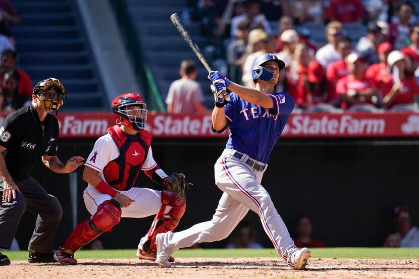 Texas Rangers' Corey Seager, right, hits a home run during the fifth inning of a baseball...