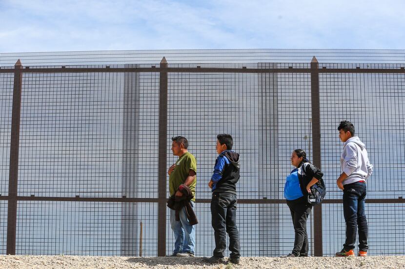 Central American asylum seekers wait as U.S. Border Patrol agents arrive to take them into...