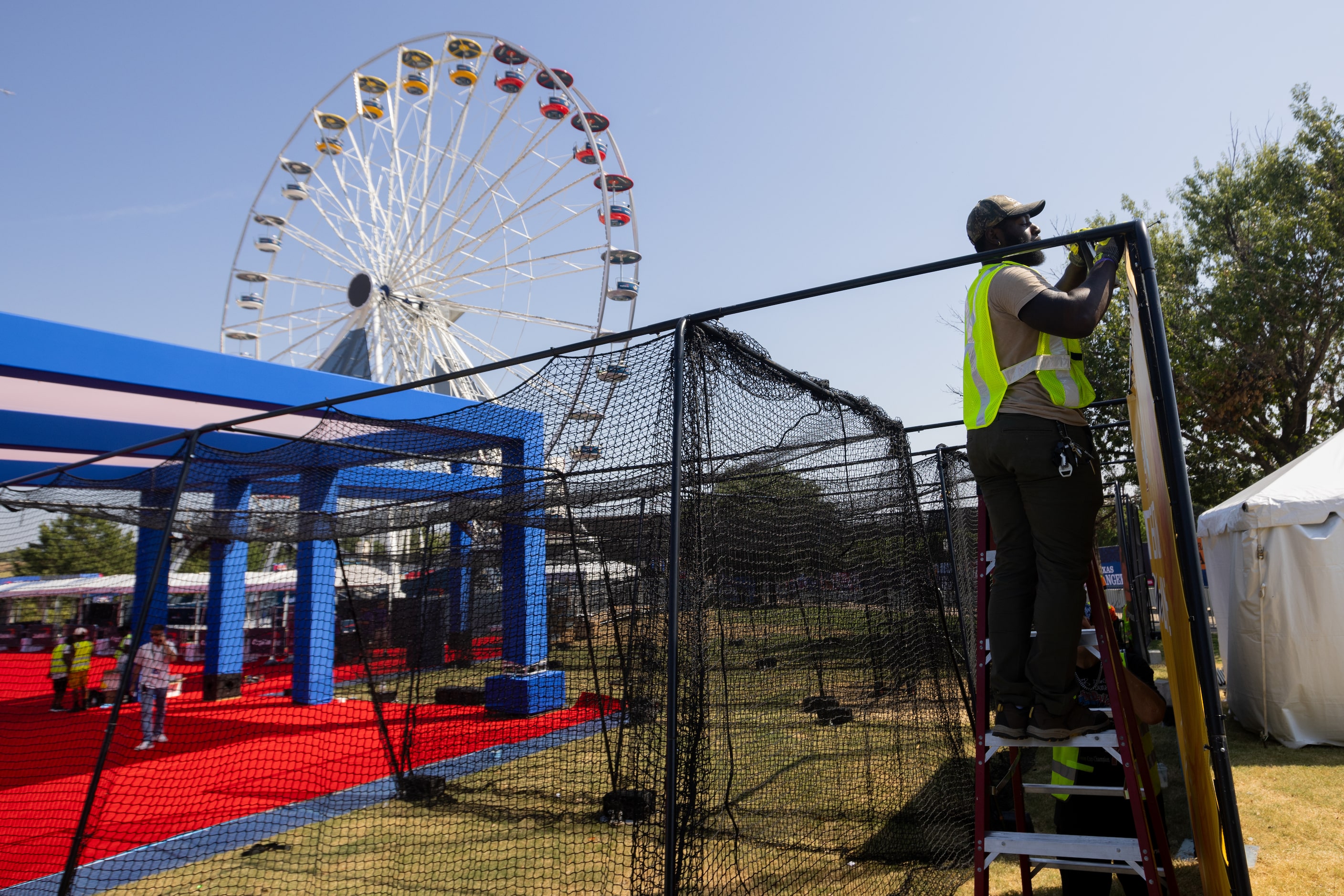 Anthony Hawkins sets up a batting cage by the Ferris wheel at MLB's All-Star Village in...