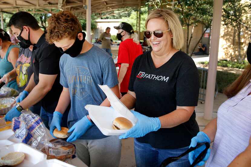 Agent Brandy Jett (center) prepares a hamburger along with her Fathom Realty family. They...