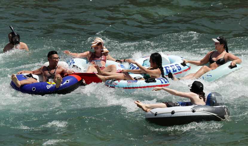 Tubers float the Comal River in New Braunfels Wednesday. As parks reopen following closures...