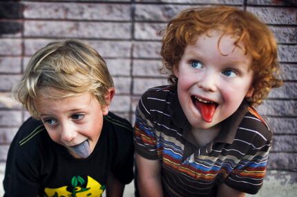 5-year-olds Aidyn Martin (left) and Logan Conrad show off their colored tongues after...
