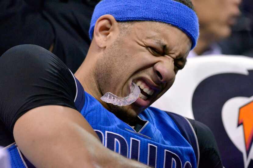 Dallas Mavericks guard Seth Curry grimaces and holds his arm after leaving the court in the...