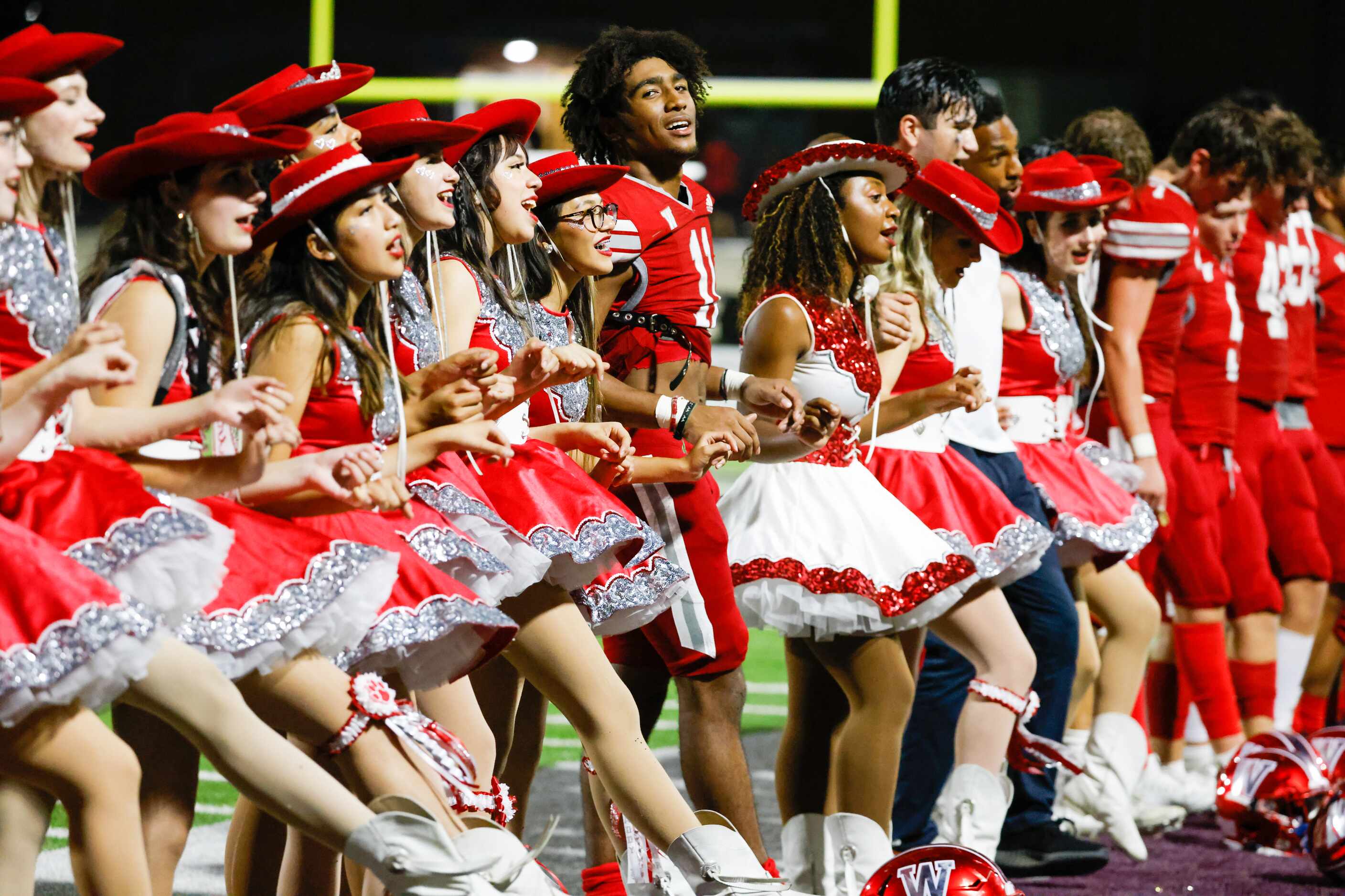 Woodrow Wilson football players join their dance team to kick to the school song after a win...