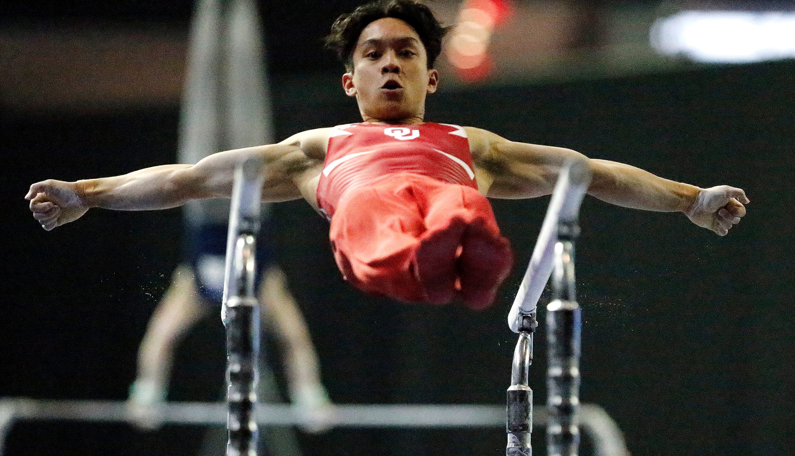 Zachary Nunez represents the University of Oklahoma in the parallel bars during the mens...