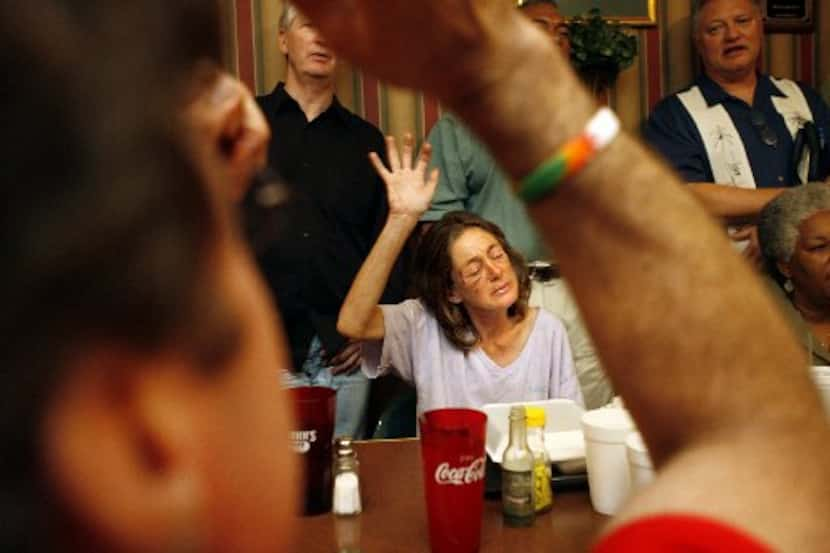 In this 2007 file photo, Sherry Mason, center, who's homeless, prays amidst businessmen,...