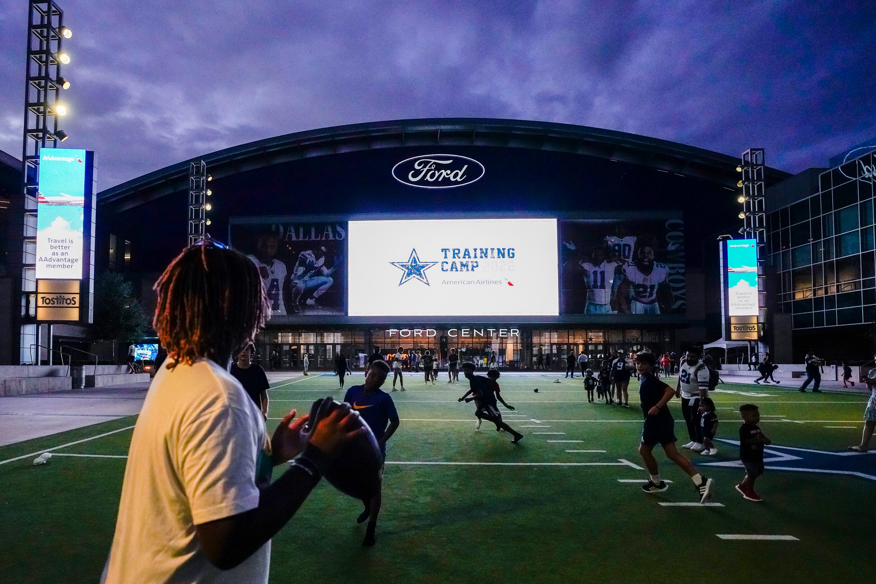 Youngsters toss a football on the plaza outside during a Dallas Cowboys training camp...