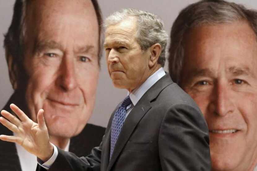 
Former President George W. Bush passes by a portrait of himself and his father former...