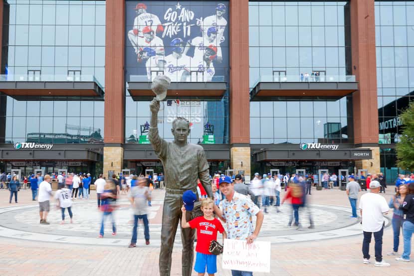 Brian Dodson and Landon, 7, of Longview, TX, takes a photo with the statue of former Texas...