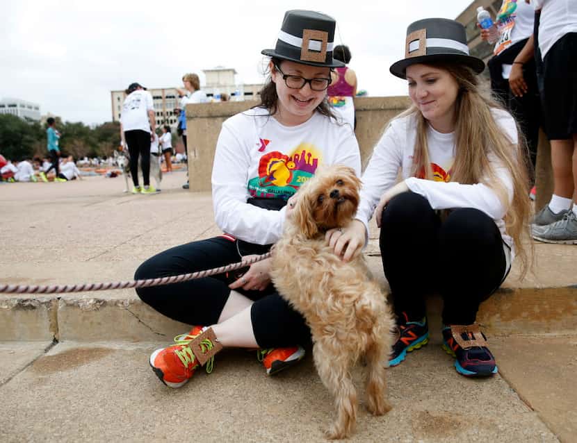 Mara Lipow (left) and Lauren Levine pet a dog named Bella at the Dallas YMCA Turkey Trot in...