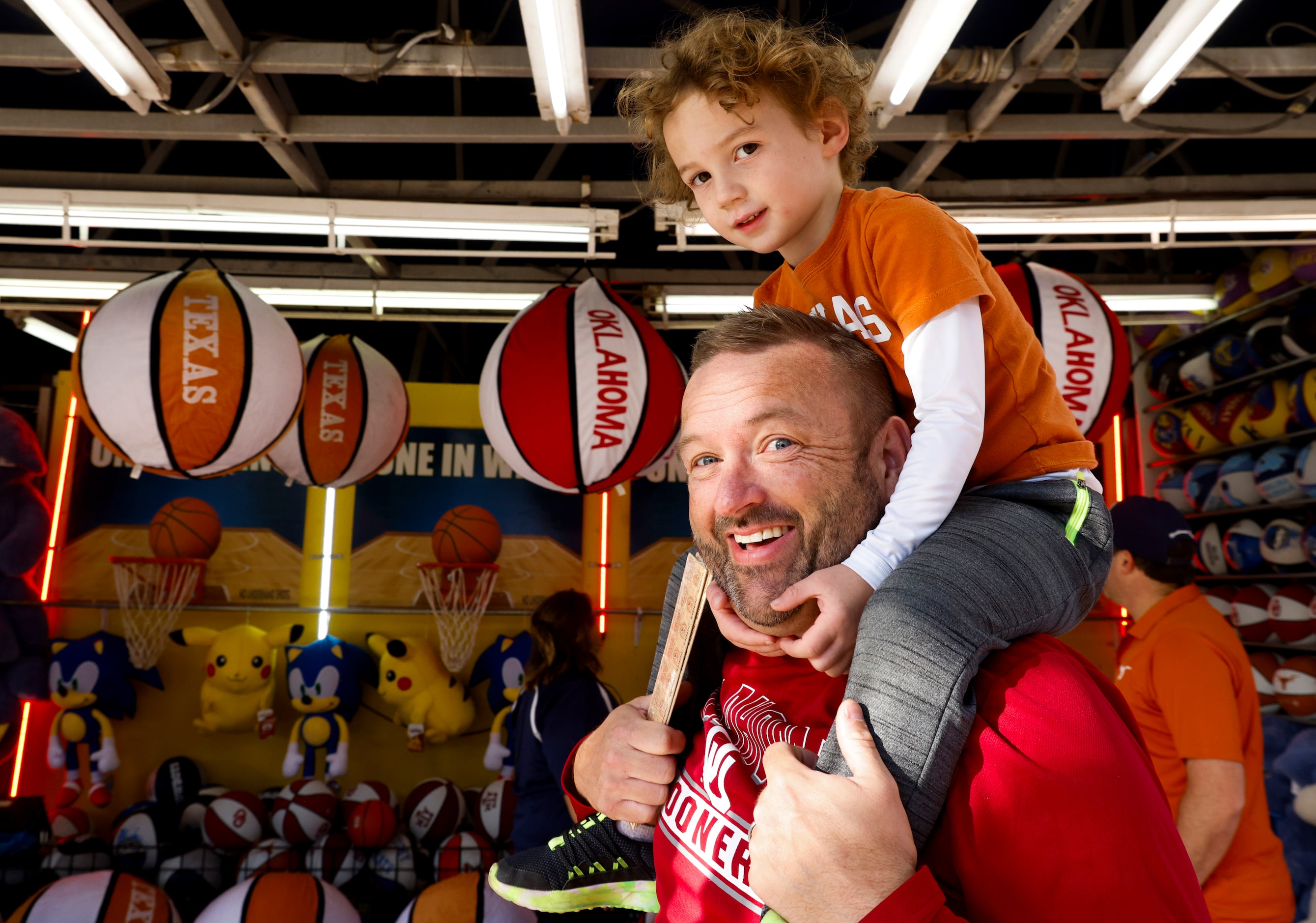 Derek Jones carrying her son Jax, 4, from Oklahoma heads toward the Cottown Bowl ahead of...