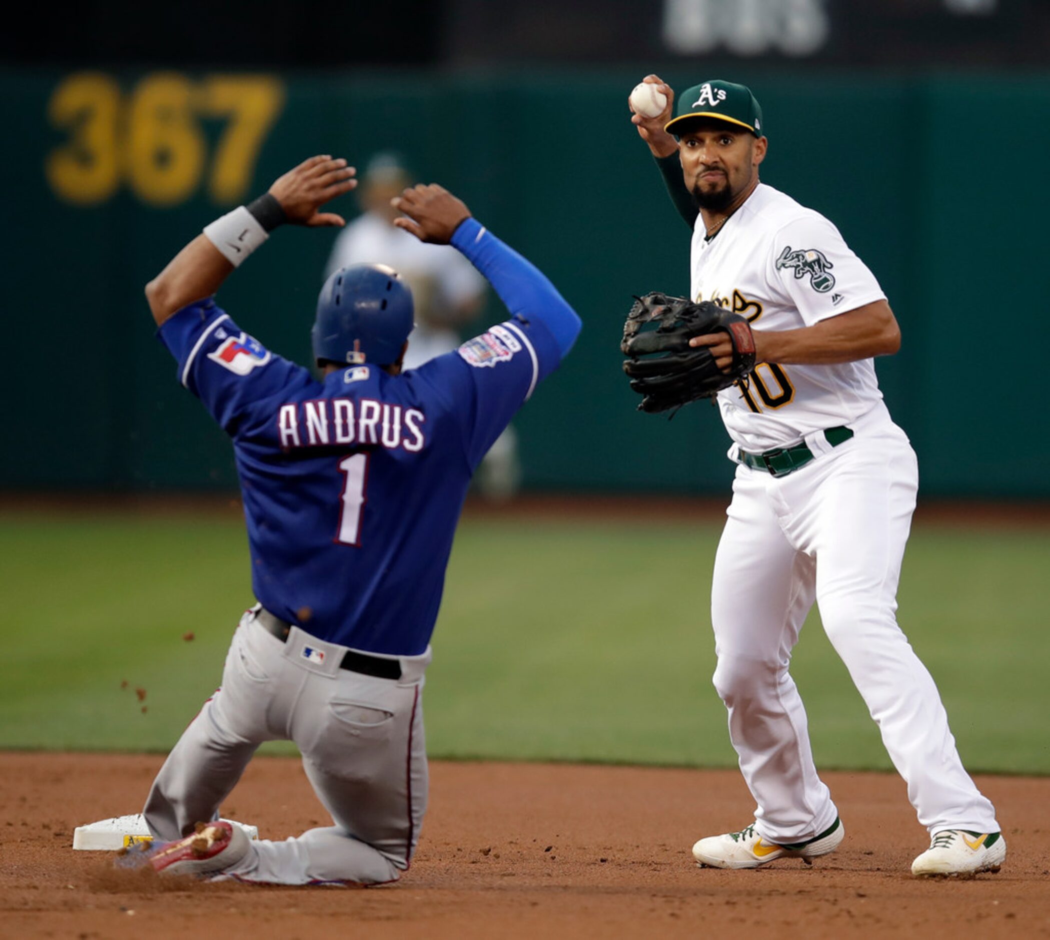 Oakland Athletics' Marcus Semien, right, prepares to throw over Texas Rangers' Elvis Andrus...