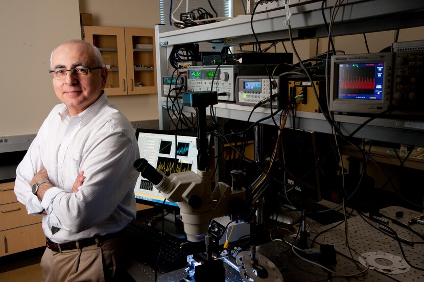 Volkan Ötügen stands in front of an instrument used to measure changes in the electric field. 