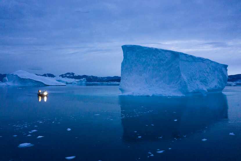 FILE - A boat navigates at night next to large icebergs in eastern Greenland on Aug. 15,...