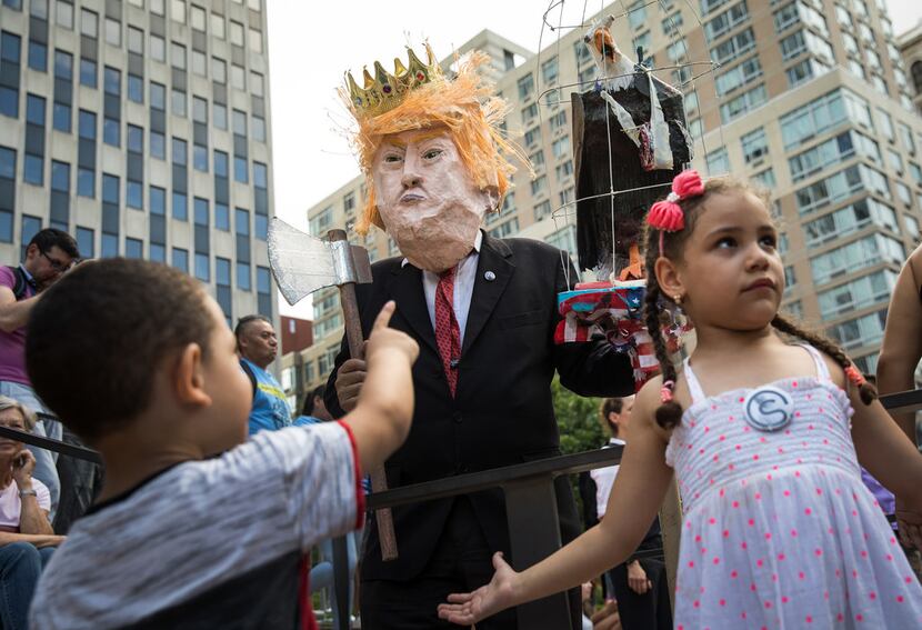 A man dressed to resemble President Donald Trump interacts with children as activists rally...