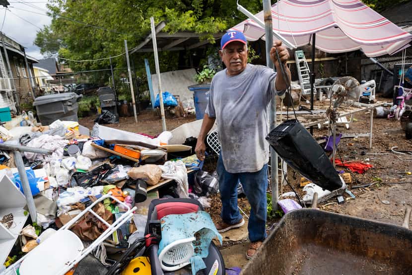 Juan Garcia cleans out the items from his home damaged by the Monday morning floods on...