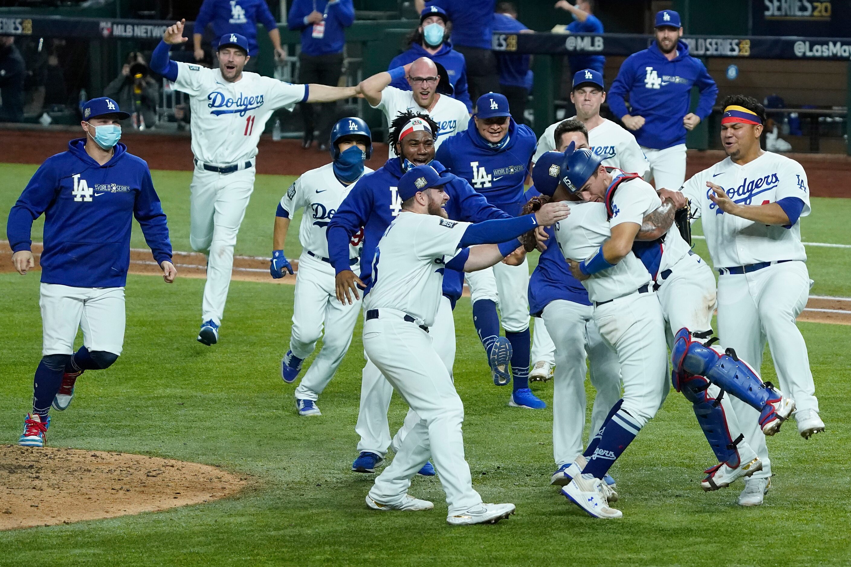 Los Angeles Dodgers players rush to join pitcher Julio Urias and catcher Austin Barnes as...