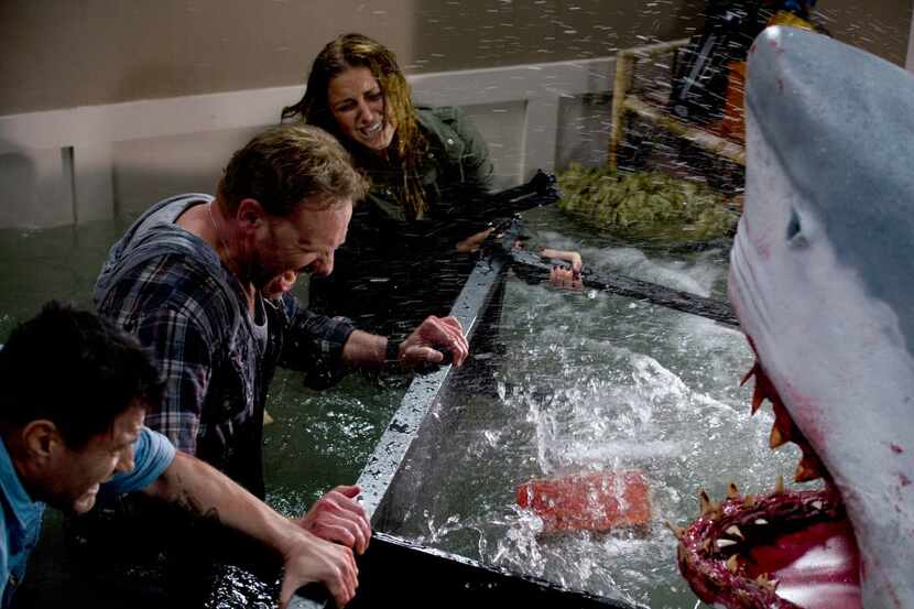 In this image released by Syfy, Ian Ziering, second left, and Cassie Scerbo battle a shark...