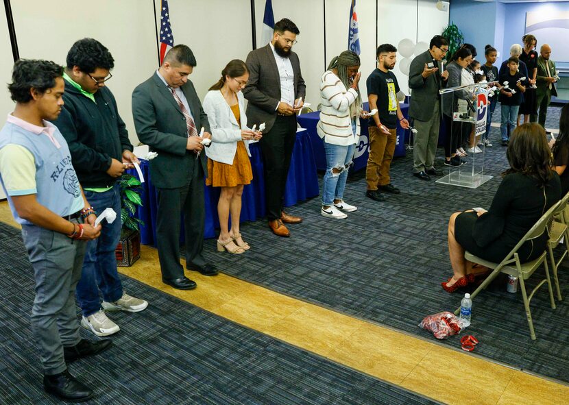 People stand for a prayer before reading the names of victims from the Robb Elementary...