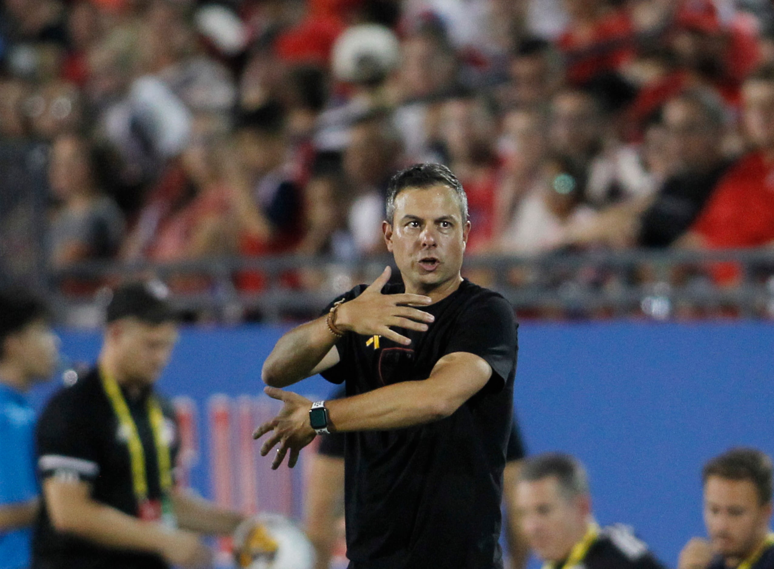 FC Dallas head coach Nico Estevez communicates with his players along the team bench area...